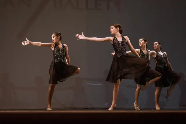 Grupo de bailarinas con vestidos negros con brillo extendiendo los brazos en una coreografía de EDC 2019.